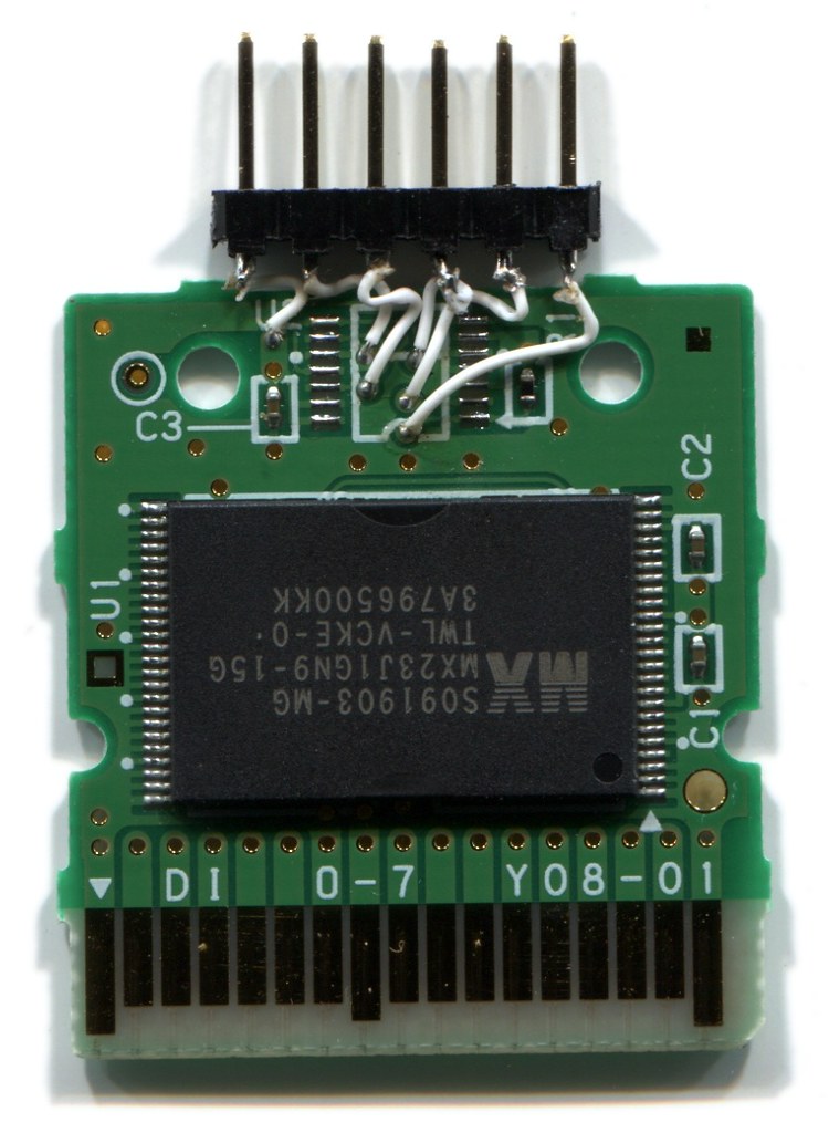 Photo of a DSi cartridge with the plastic shell removed, and
        wires soldered to the SPI traces.