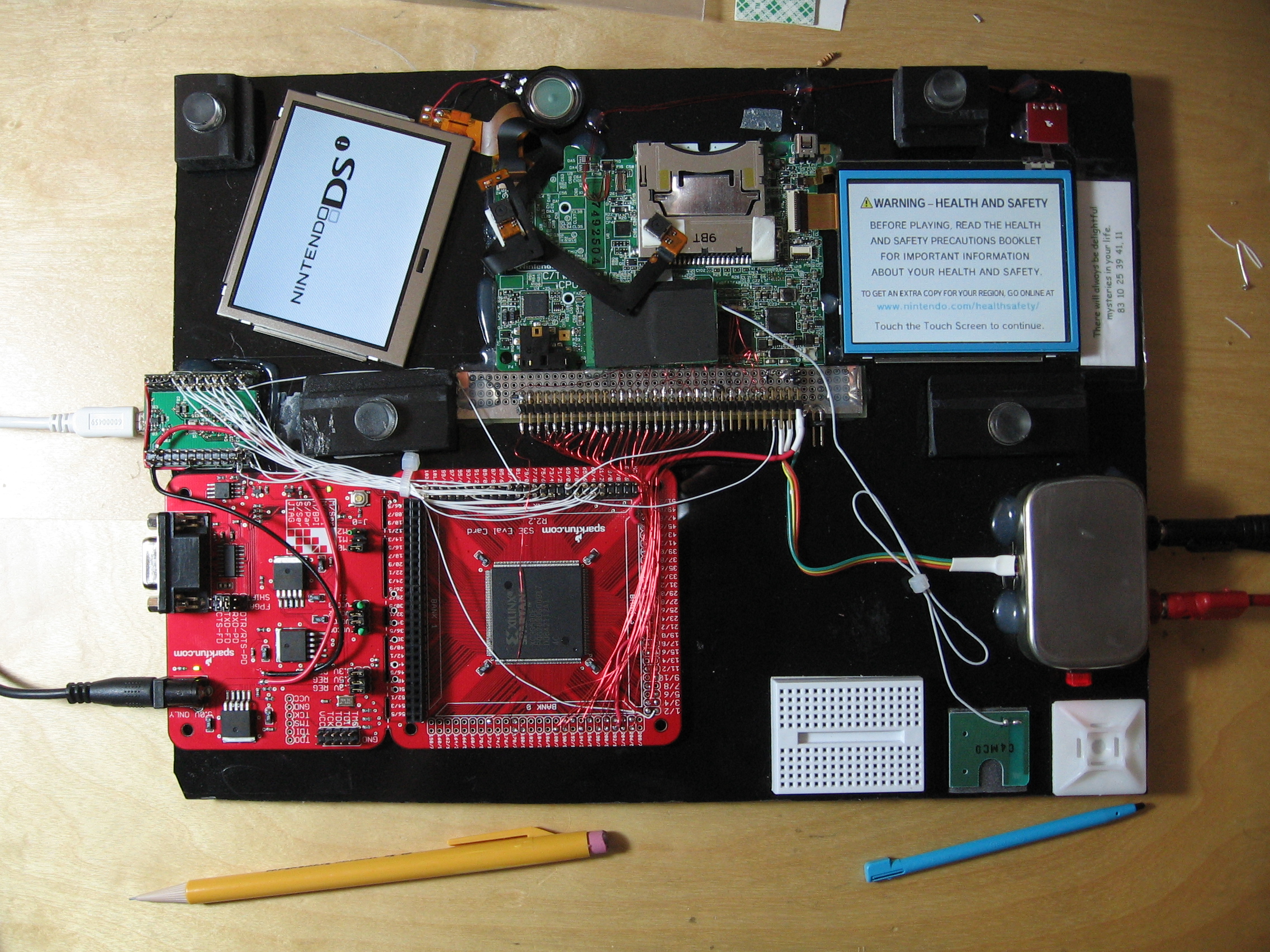 Photo of scanlime's RAM tracer. It shows the innards of a DSi
        connected to an FPGA devboard with lots of ugly wiring. It somehow still
        lives.